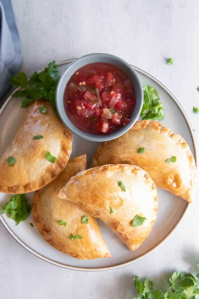 empanadas on platter with sauce