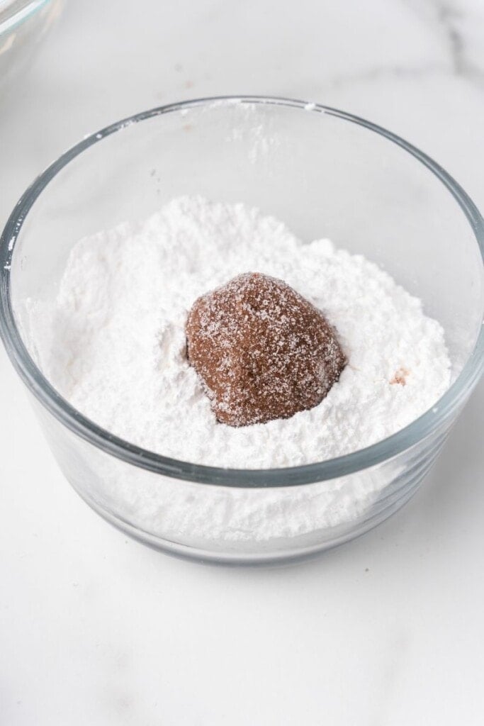 dipping cookie dough into powdered sugar