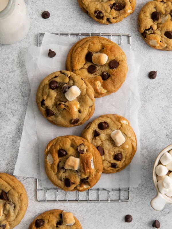 Chocolate chip marshmallow cookies on a counter with parchment paper and a wired rack.
