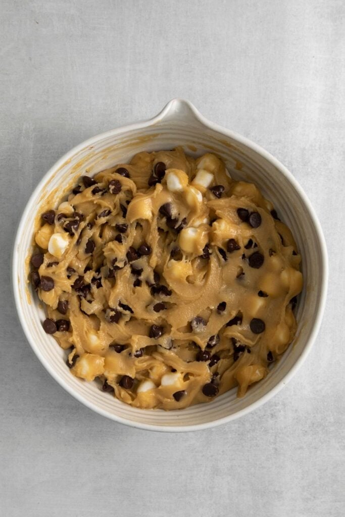 Chocolate chip and marshmallow cookies batter in a mixing bowl about to be scooped out.