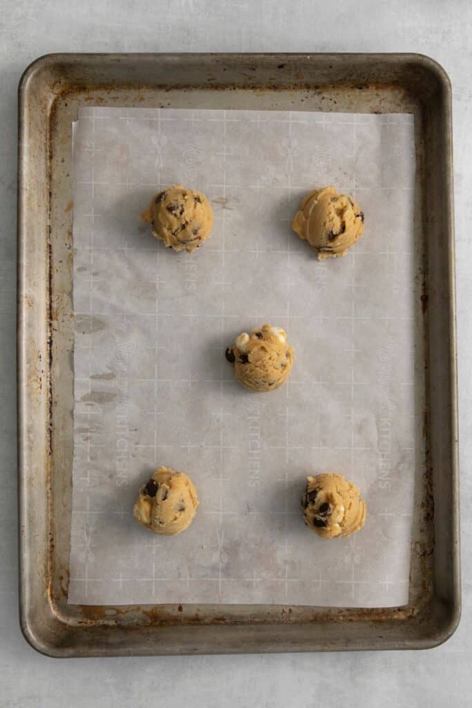 Chocolate chip marshmallow cookie dough balls on a baking sheet with parchment paper.