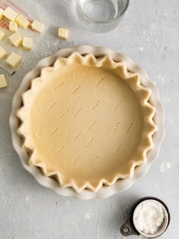 Easy pie crust recipe in a pie pan with the sides crimped and fork holes on the bottom about to be baked.