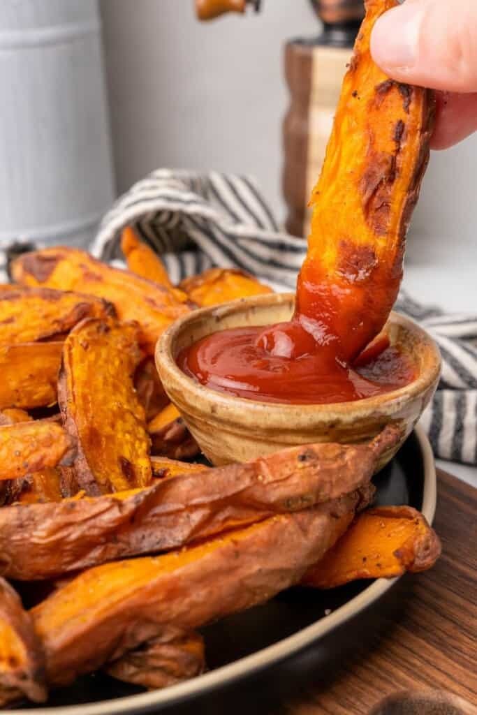 dipping air fryer sweet potato wedge in ketchup