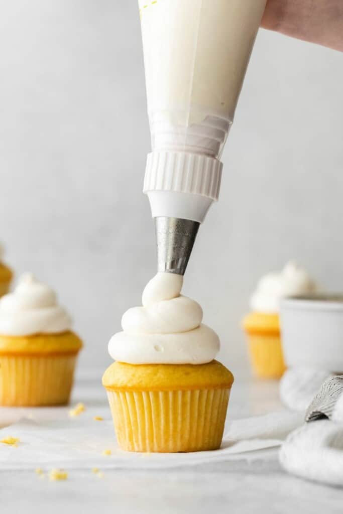 adding frosting to cupcake