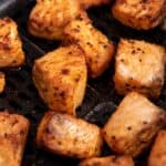 Close up of air fryer salmon bites in an air fryer basket.