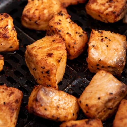 Close up of air fryer salmon bites in an air fryer basket.