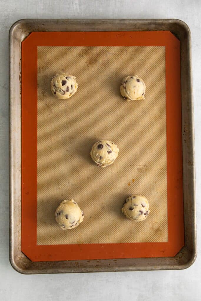 Chocolate chip cookie recipe with no brown sugar dough balls on a silicone mat on a baking sheet.