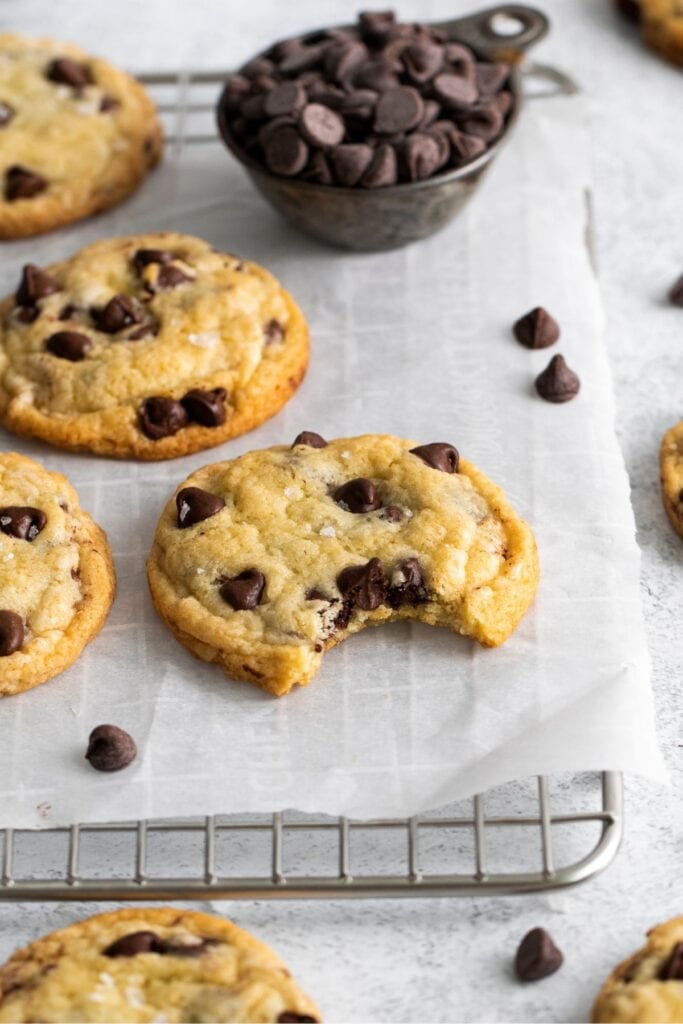 Chocolate chip cookies with no brown sugar on a wire rack with a bite taken out of the one.