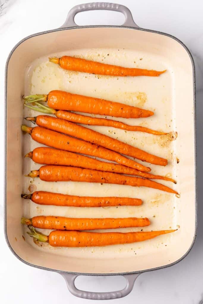 Carrots in a baking dish partially roasted to make roasted asparagus and carrots.