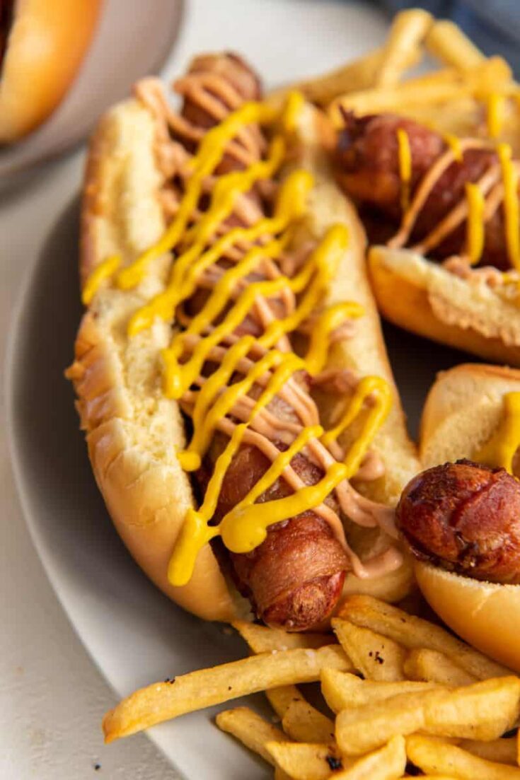 bacon wrapped hot dog drizzled in mustard