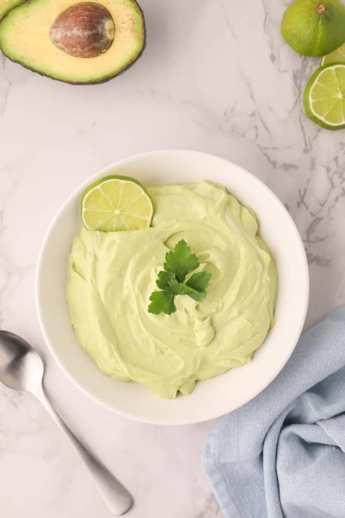 Overhead view of avocado crema with an avocado and spoon