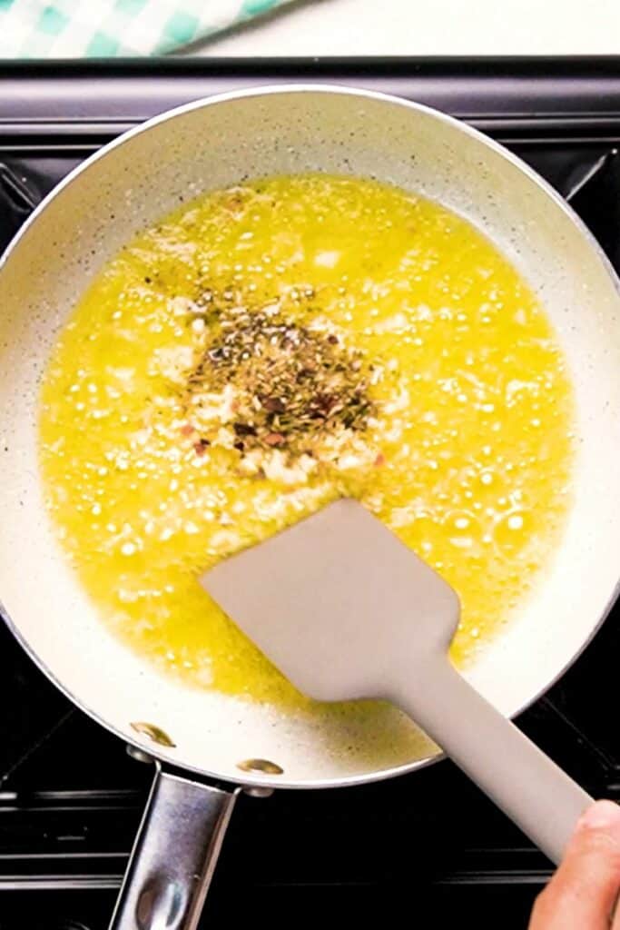 Oil and melted butter with seasoning in a pan being stirred