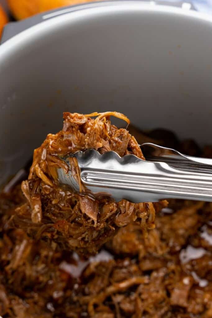 picking up shredded pork with tongs