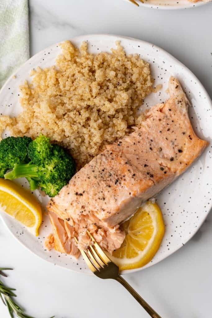 white plate with salmon, broccoli, and lemon slices