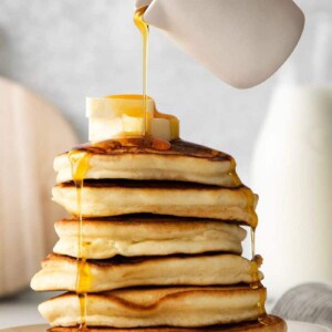 adding syrup to pancakes
