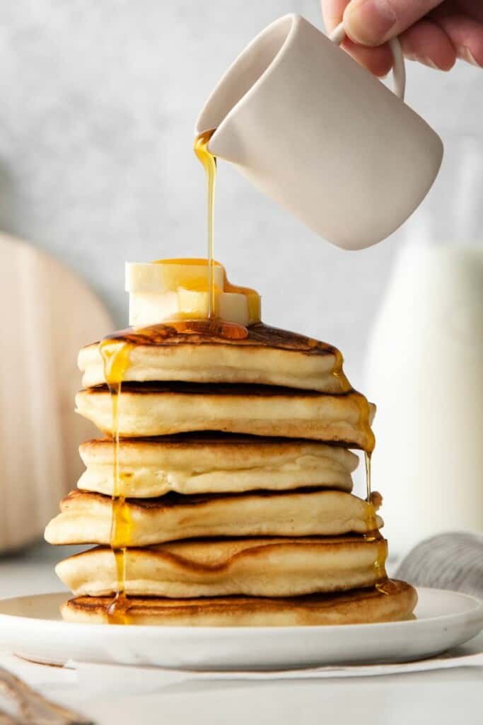 adding syrup to pancakes