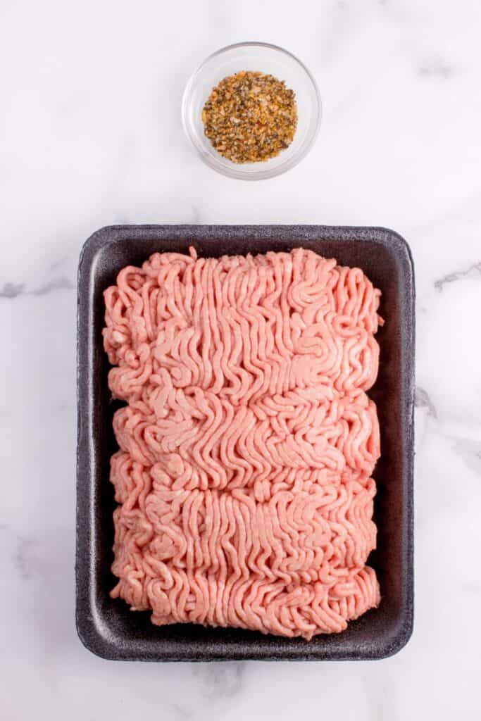 Ground beef in packaging and Montreal steak spice on the counter