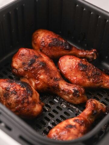 Close up of cooked air fryer chicken drumsticks in the air fryer basket.