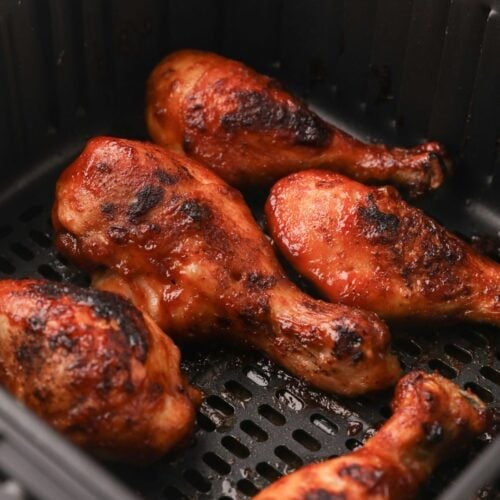 Close up of cooked air fryer chicken drumsticks in the air fryer basket.