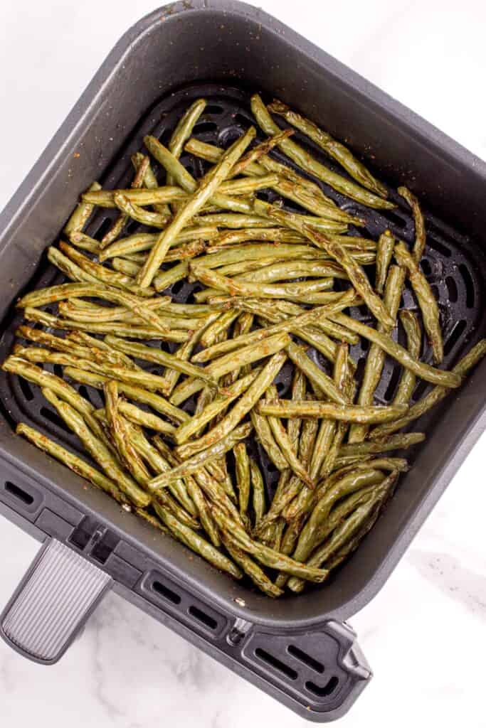 Cooked green beans in the air fryer basket.