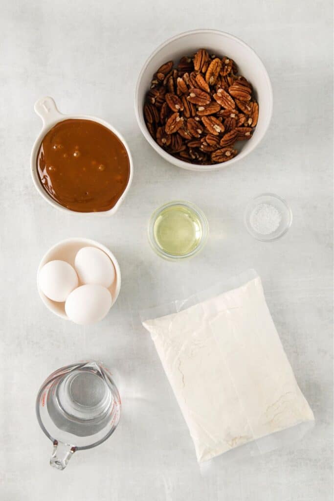 Ingredients needed to make pecan upside down cake: pecans, caramel sauce, salt, yellow cake mix, water, vegetable oil, and eggs.