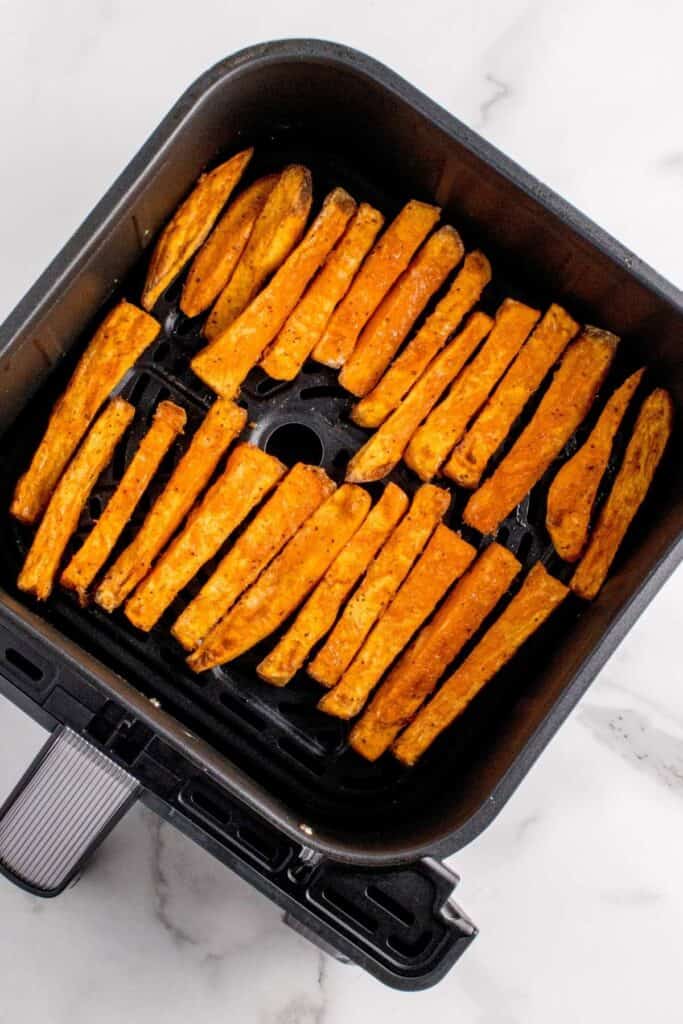 Air fried sweet potato fries inside an air fryer basket.