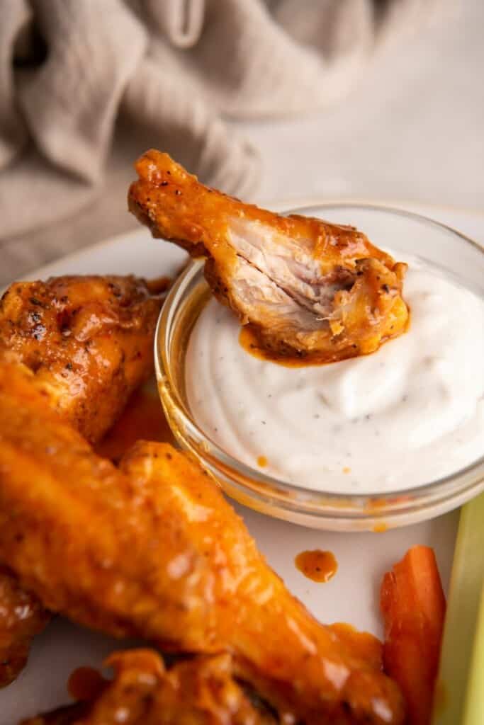 dipping buffalo wing into sauce