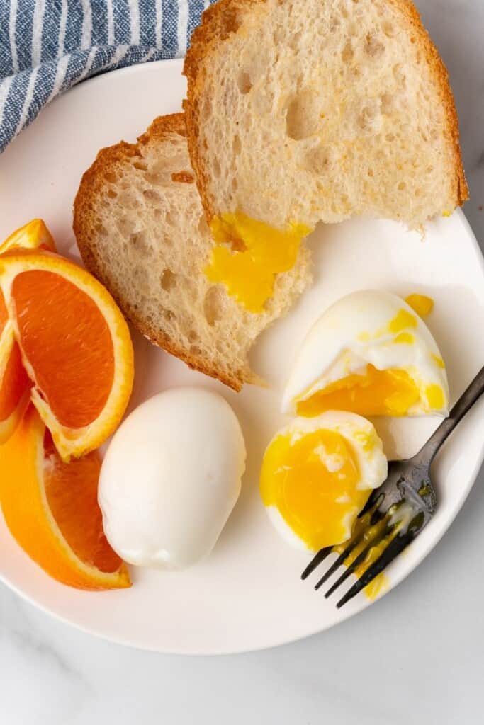 soft boiled egg with bread and orange slices