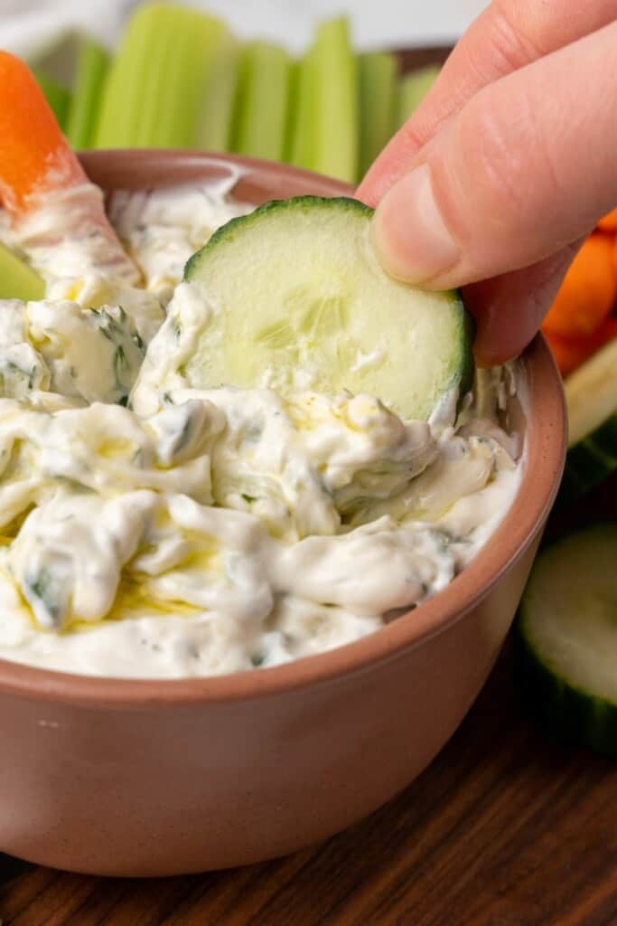 dipping cucumber in Tzatziki Sauce