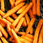 Sweet potato fries in an air fryer basket cooked.