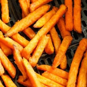 Sweet potato fries in an air fryer basket cooked.