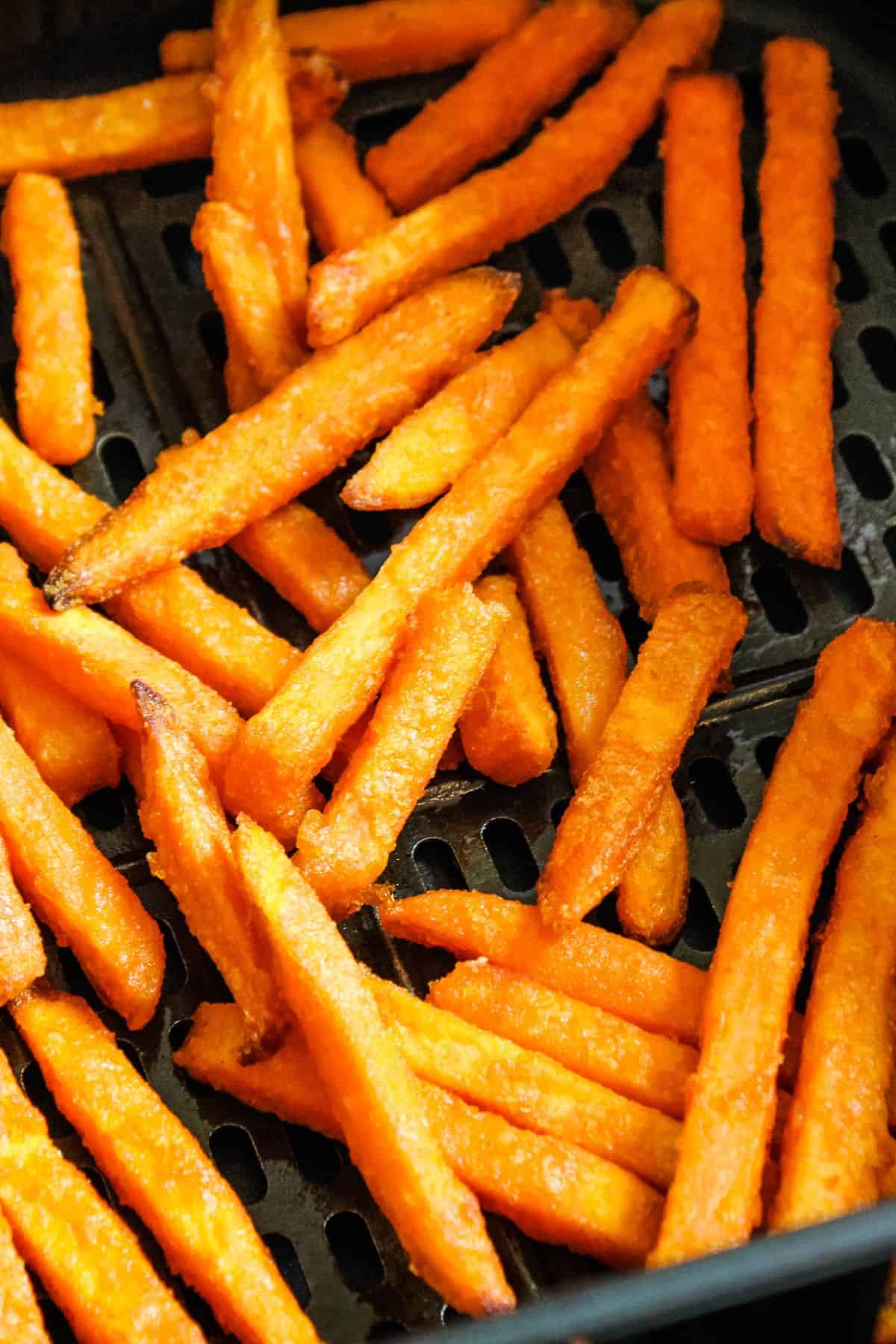 Sweet potato fries in an air fryer basket cooked.