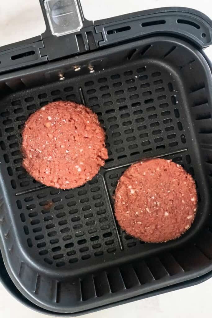 burger patties in an air fryer basket