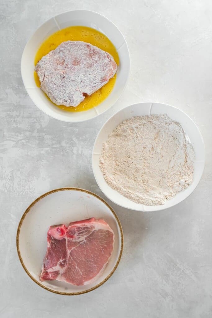 dipping floured pork chop in egg mixture