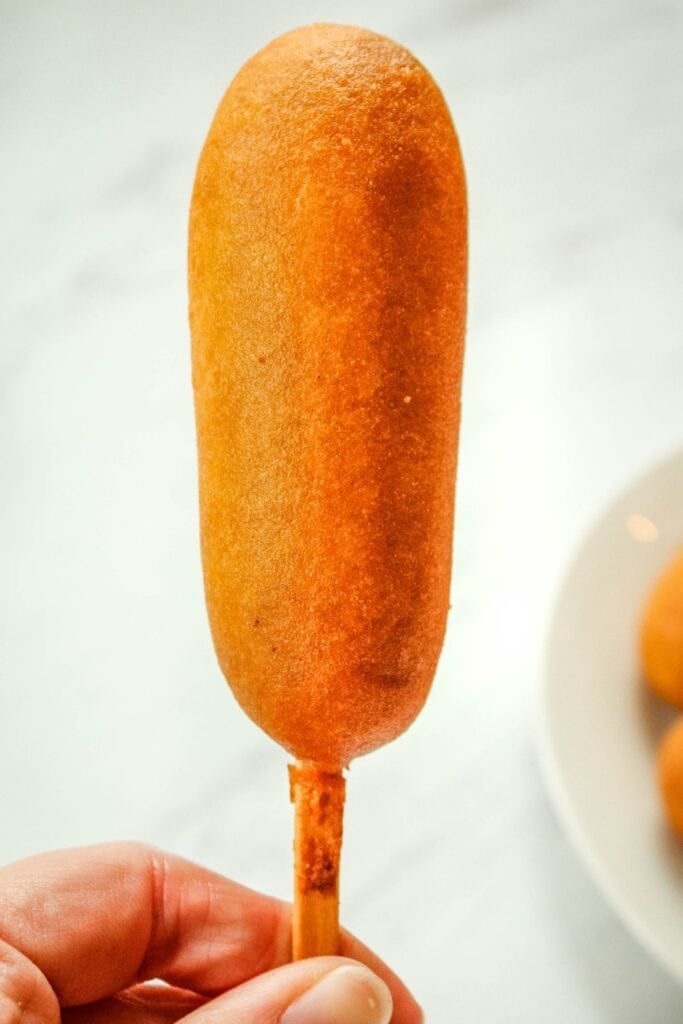 Person holding a cooked air fryer corn dogs.