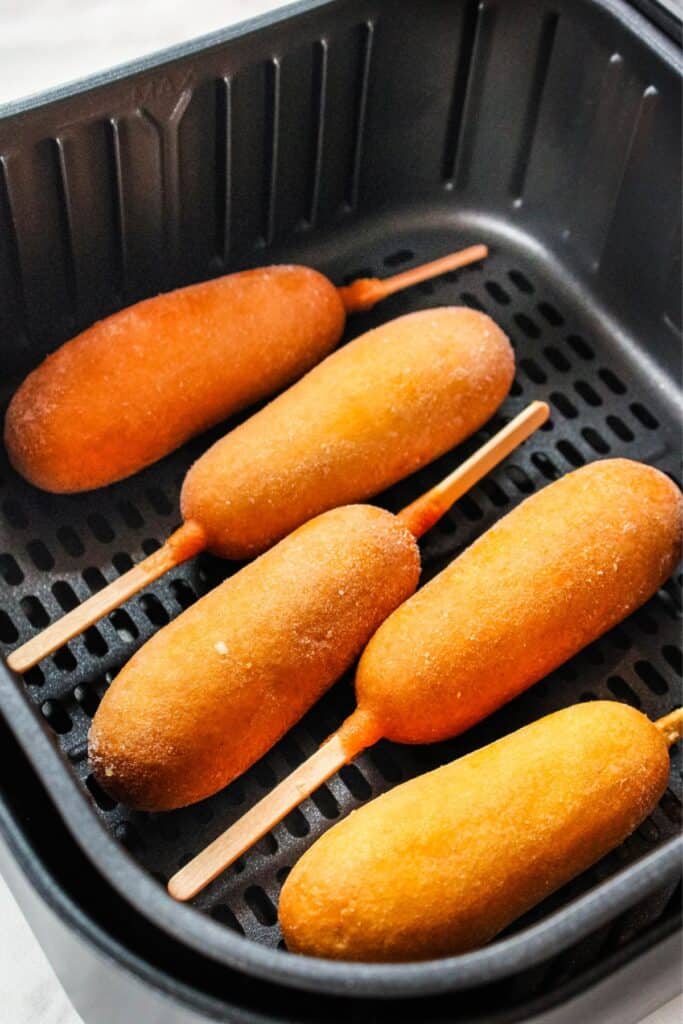 Frozen corn dog in the air fryer basket.