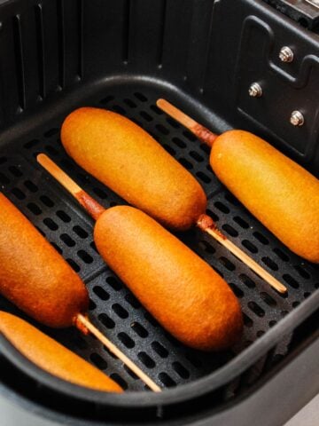 Cooked corn dogs in the air fryer basket.