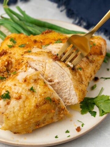 fork cutting into a piece of split chicken breast