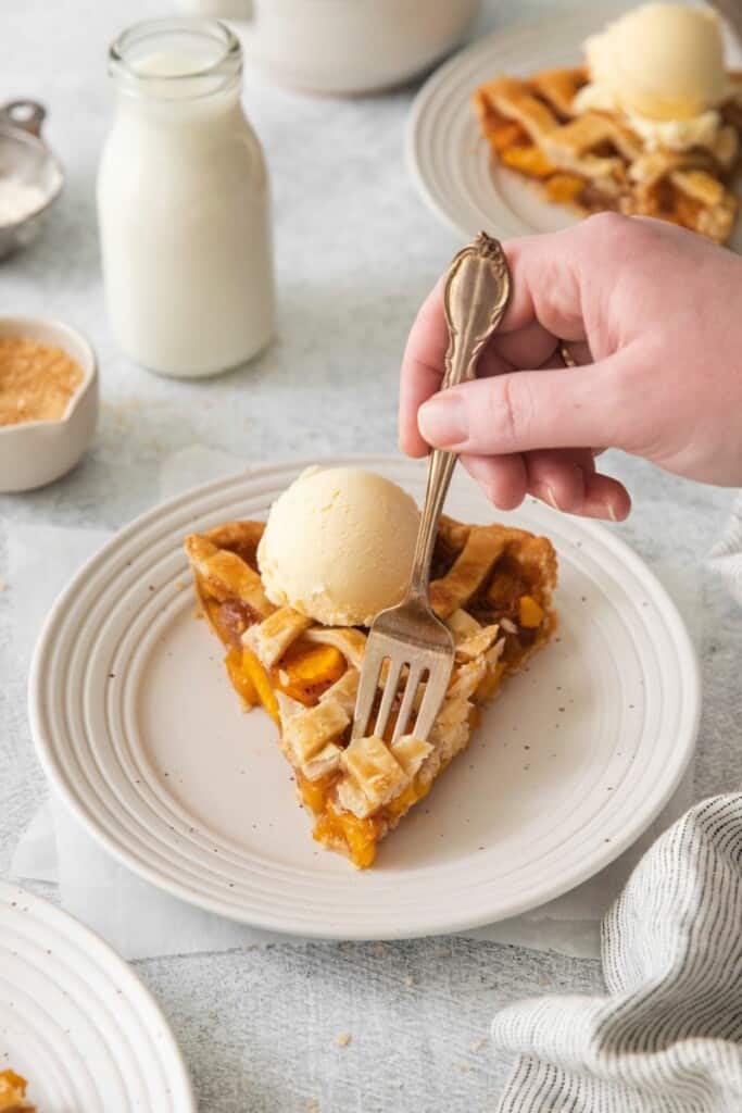 fork digging into a piece of peach pie