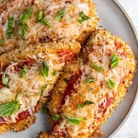 Close-up of air fryer chicken Parmesan on a white plate.