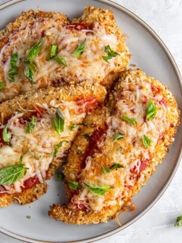 Close-up of air fryer chicken Parmesan on a white plate.