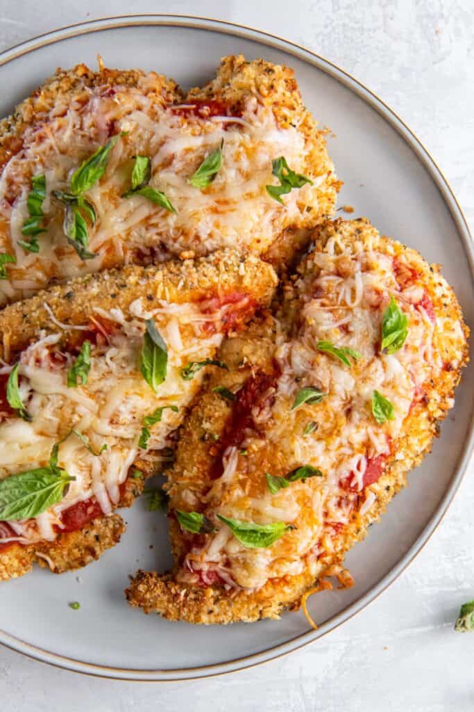 Close-up of air fryer chicken Parmesan on a white plate.