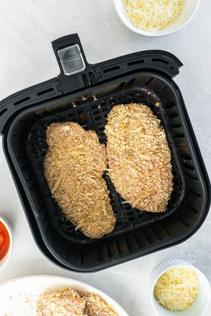 Chicken Parmesan in an air fryer baskeet about to be cooked.
