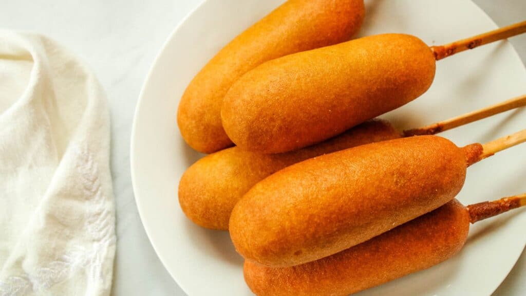 Air fryer corn dogs on a white plate.