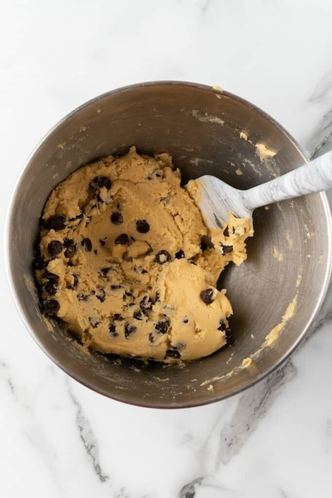 Overhead view of ingredients for air fryer cookies mixed together in a silver mixing bowl.