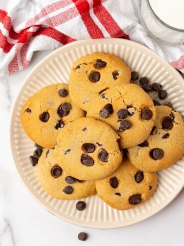 Overhead view of chocolate chip cookies prepared in an air fryer on an off white plate.