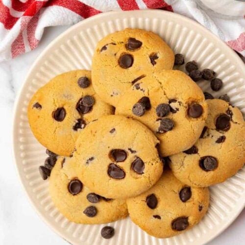 Overhead view of chocolate chip cookies prepared in an air fryer on an off white plate.