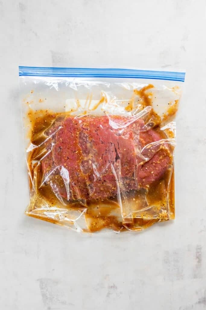 Overhead view of cube steak marinating in a Ziplock bag.