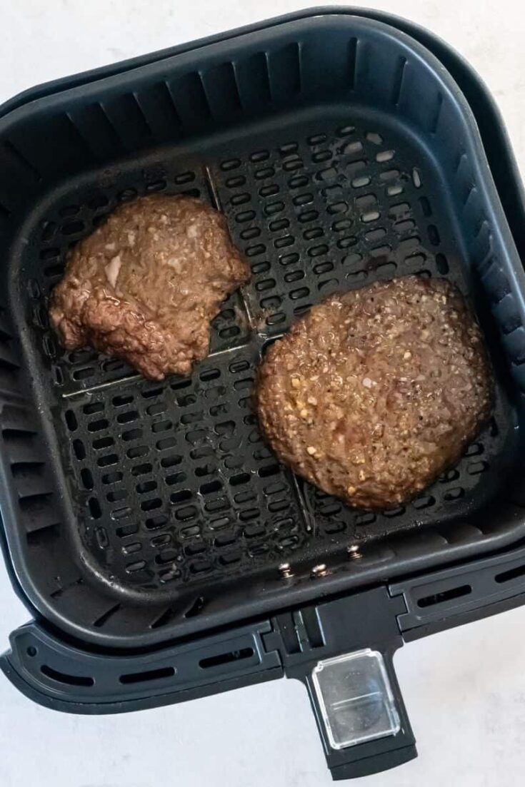 Overhead view of two cube steaks in an air fryer basket.