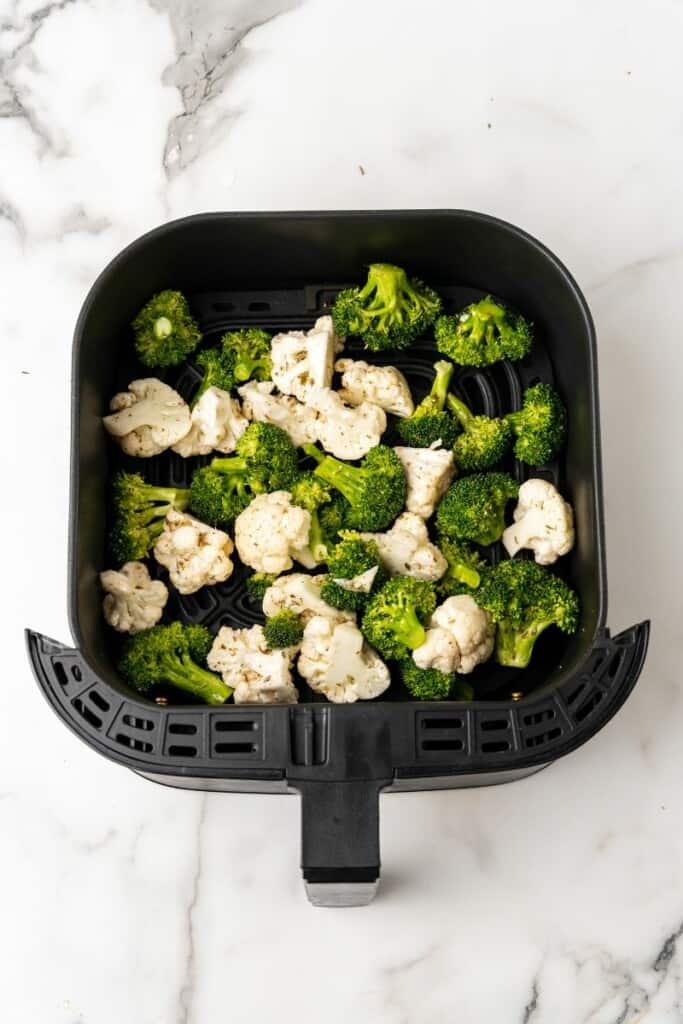 Broccoli and Cauliflower in a black air fryer basket ready to be cooked.